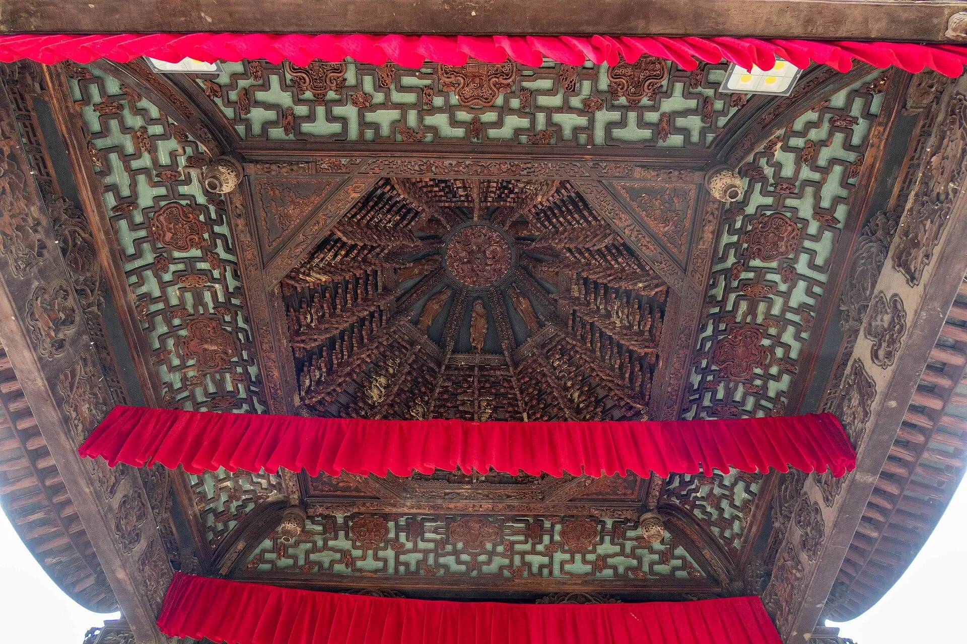 The caisson ceiling above the stage, its carved wooden brackets spiraling upward.